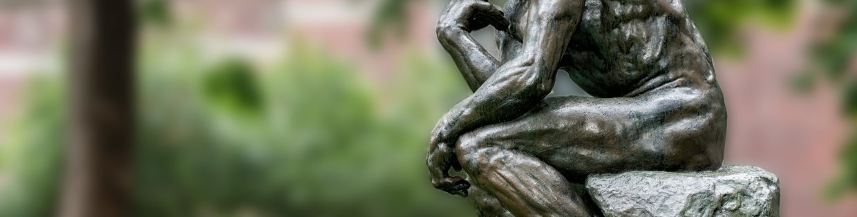 A bronze statue of a person with hands on chin, contemplating. 