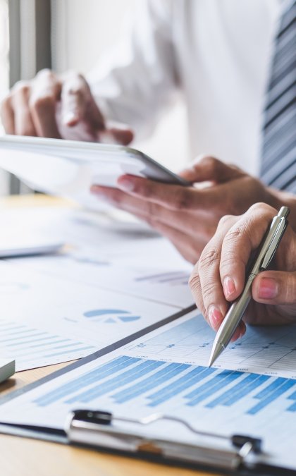 business management header image with people looking over clipboards with charts.