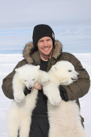 Assistant Professor John Whiteman holding two polar bear cubs