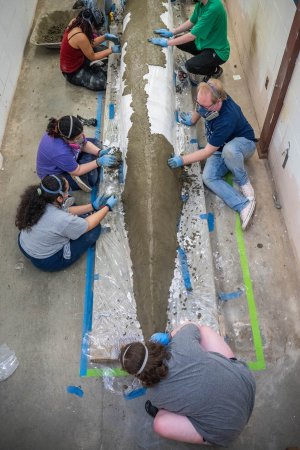 Team places wet concrete on canoe mold