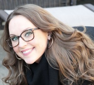 A smiling woman wearing glasses and a black top. 