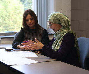 Two students collaborate around a table in a classroom.