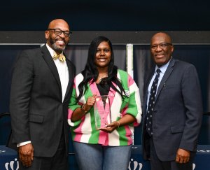 A woman holds an award while standing between two men.