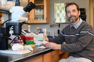Professor Dan Barshis, Ph.D., in his lab with scientific equipment on a table 