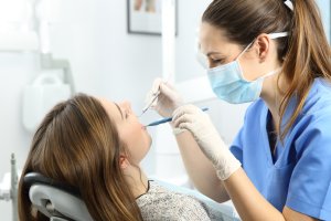 Dental professional examining patient teeth at office