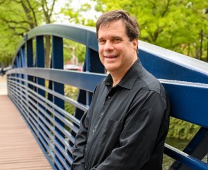Jim Blando, Ph.D., stands outside on a bridge