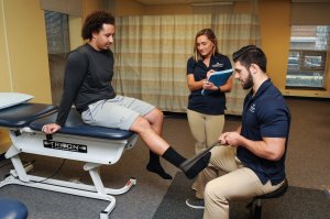 Two students inspecting a patient's leg