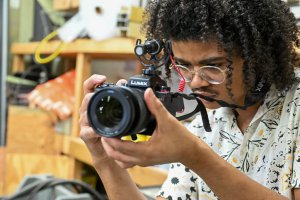 JaVaughn Davis with a camera in a workshop