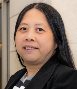 A woman in a dark blue jacket smiles and poses.