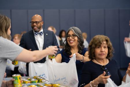Faculty, staff, and students packing canned food in bags to be donated