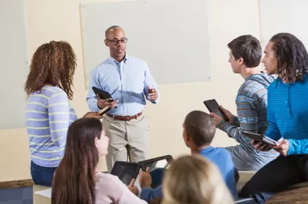 African American man (50s) teaching a diverse group of high 