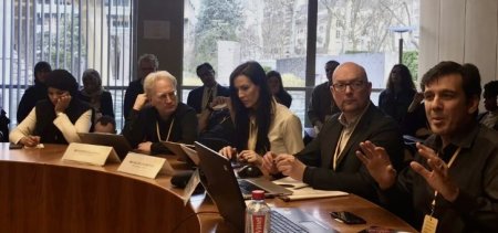 Helen Crompton, Ph.D., sites at a desk with other people. 