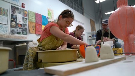 Student sculpts with clay in art studio.