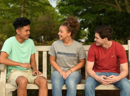 students conversing on an outdoor bench