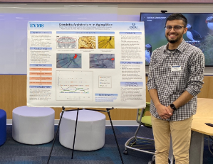 Young man standing next to presentation poster
