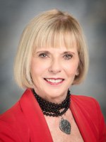 Woman with blonde hair wearing red jacket smiles at the came