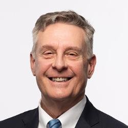 Dr. Pike has short gray hair, is wearing a dark suit with sa