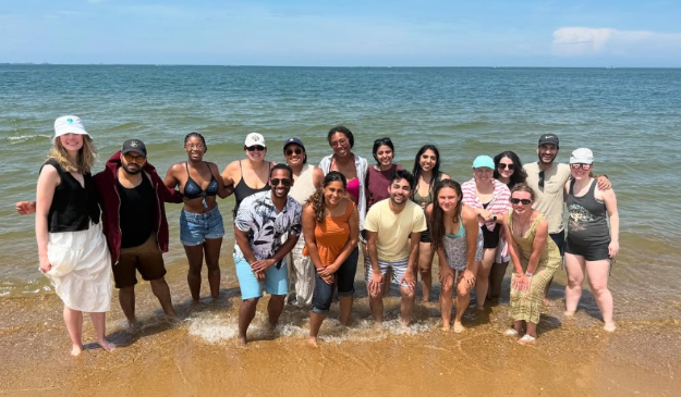 Group shot of residents on the beach with the ocean behind t