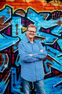 John Baaki in front of graffiti art.