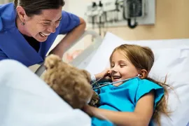 A fellow and patient laugh as the patient uses a stethoscope
