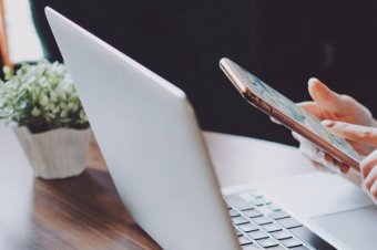 Young hipster woman using smartphone and laptop in office or