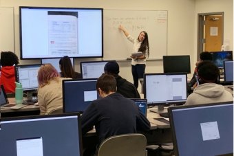 Rachel Gu stands at whiteboard teaching class