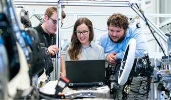 Three students working on a laptop