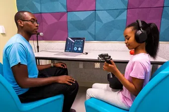A child sits in a colorful room and plays a ukelele as a cou