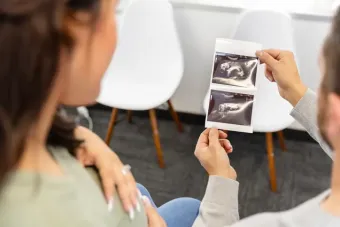 A view over the shoulders of an unrecognizable expectant cou