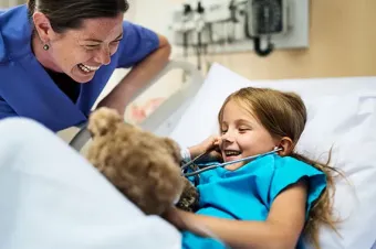 A fellow and patient laugh as the patient uses a stethoscope