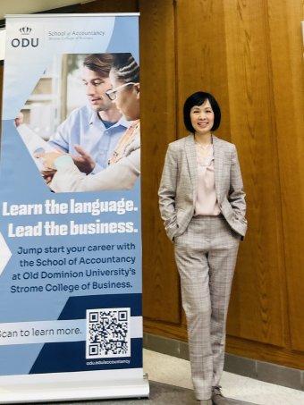 Dr. Hong Kim Duong standing beside School of Accountancy sign.