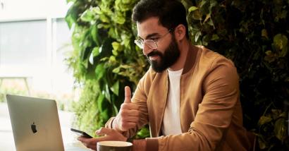 Man working on laptop giving thumbs up