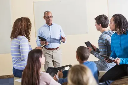 African American man (50s) teaching a diverse group of high 