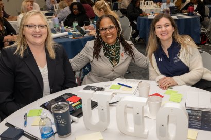 Three women at a table at the academic affairs summit.