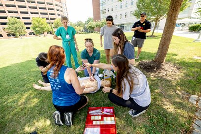 Group of medical students gather on Lester Lawn at EVMS campus to practice medical procedures on mannequin.